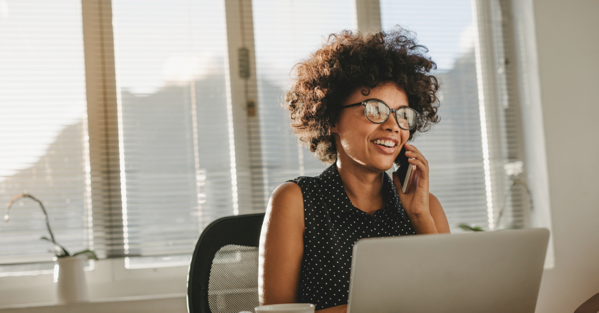 Businesswoman sitting at her desk talking on a mobile phone