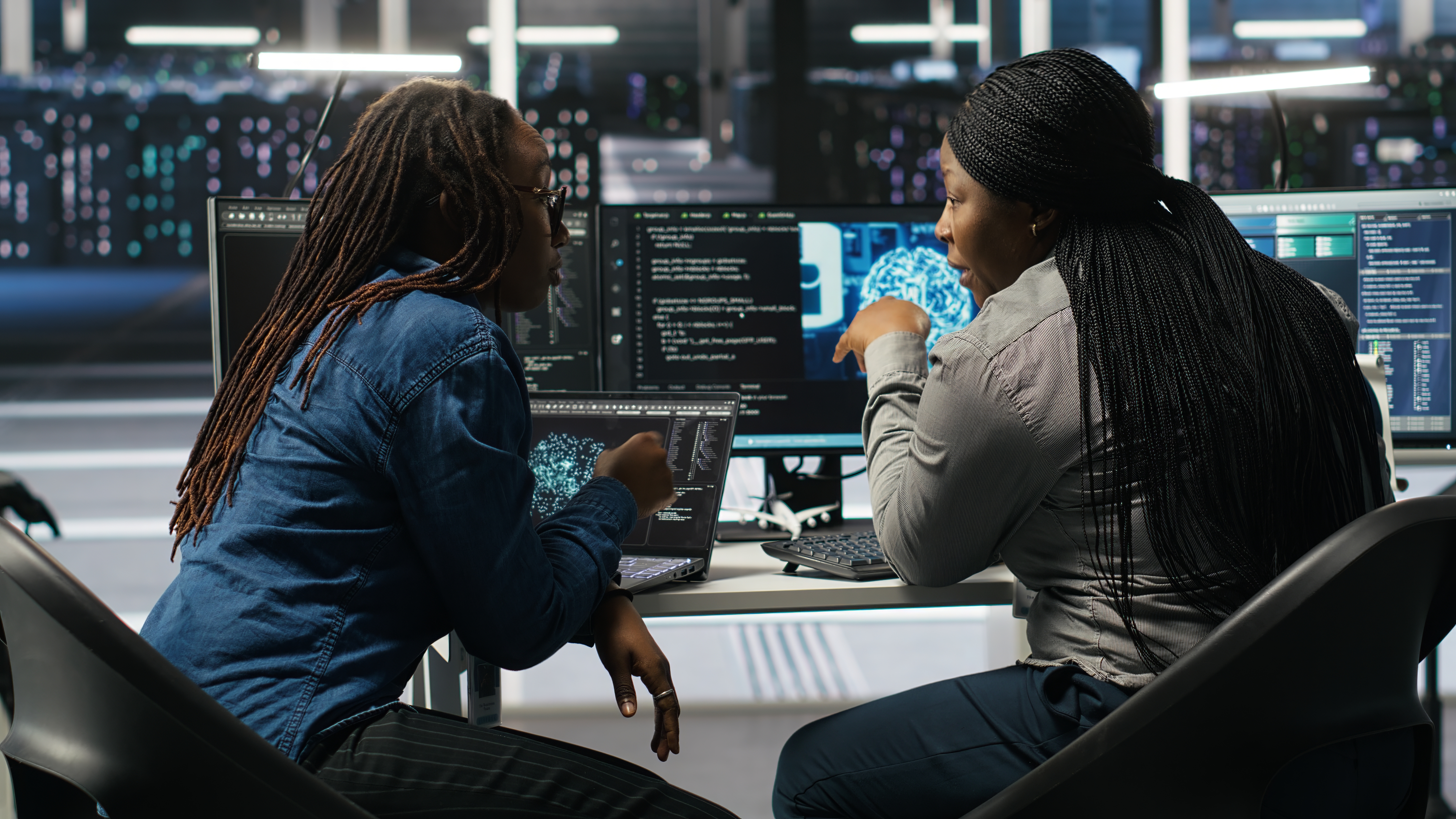 This is an image of two women looking at data on a laptop and monitor.