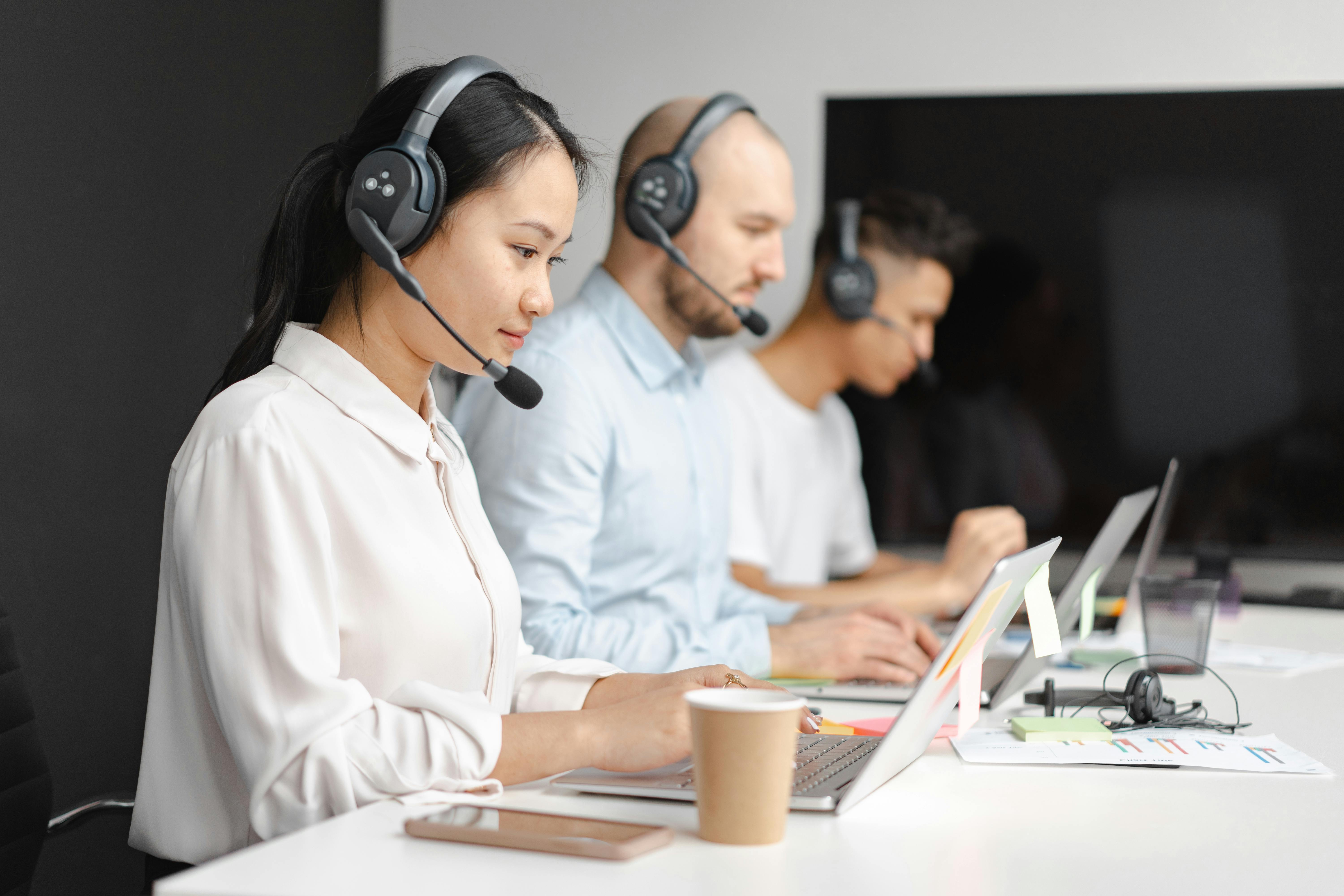 This is an image of people working at a desk with headsets on.
