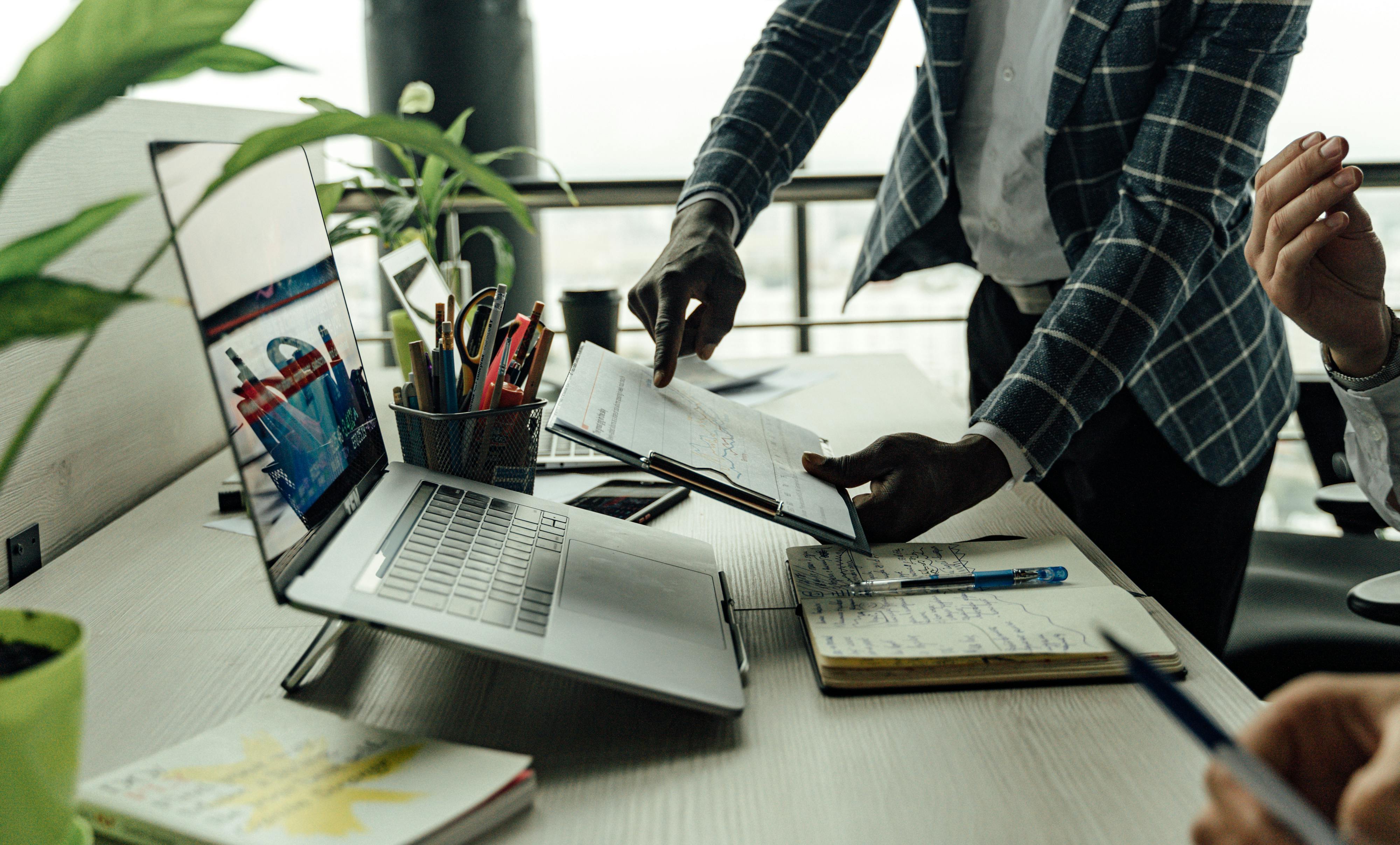 This is an image of someone pointing to a document to someone sitting at a desk.